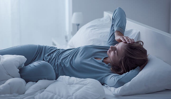 Frau liegt schlaflos im Bett Frau mit Schlafstörungen durch Wechseljahre