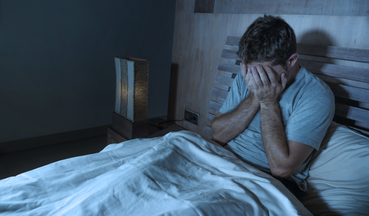 Mann sitzt schlaflos im Bett Mann sitzt schlaflos im Bett